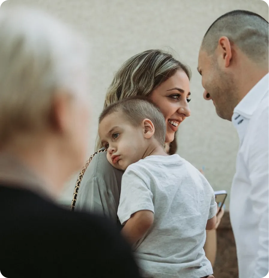 A family of four, including a child, is gathered together, smiling and interacting warmly.