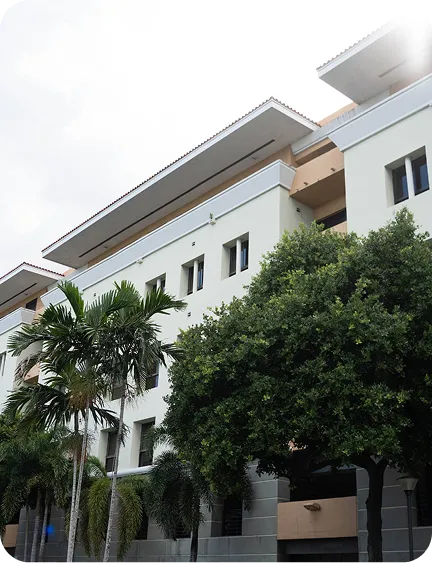 A modern building with trees in front, under a cloudy sky.