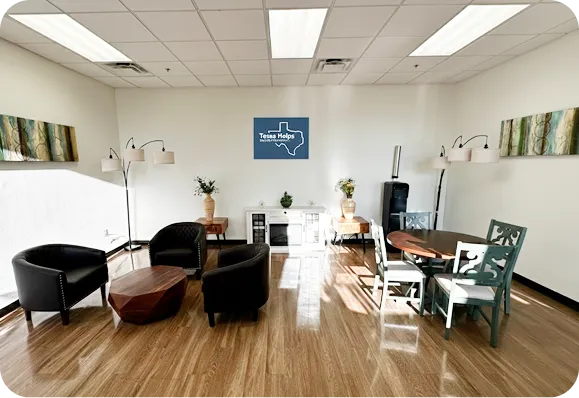 A modern office space with black chairs, wooden table, plants, and Texas-themed decor.